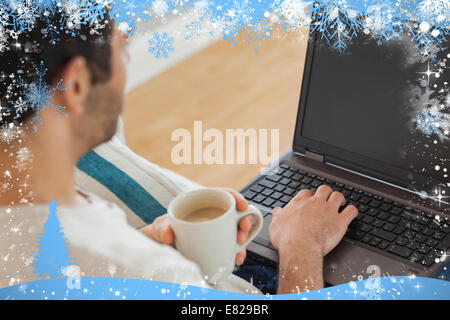 Marrone uomo dai capelli tenendo il caffè usando il suo computer portatile Foto Stock