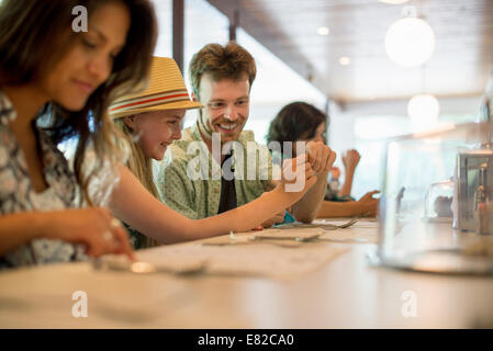 Un gruppo di amici seduti al bar in un diner. Controllare i loro telefoni cellulari. Foto Stock