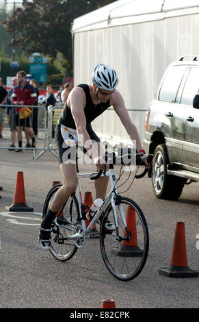 Concorrente maschile di lasciare la zona di transizione in bicicletta nel Warwickshire Triathlon, Stratford-upon-Avon, Regno Unito Foto Stock