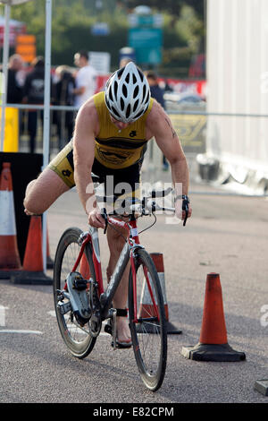 Concorrente maschile di lasciare la zona di transizione in bicicletta nel Warwickshire Triathlon, Stratford-upon-Avon, Regno Unito Foto Stock