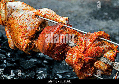 Pollo e carne di maiale messi a disposizione rotisserie ​in natura. Foto Stock