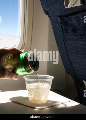 Il passeggero versando Ginger ale in una tazza di plastica a bordo del velivolo onTray Tabella, STATI UNITI D'AMERICA Foto Stock