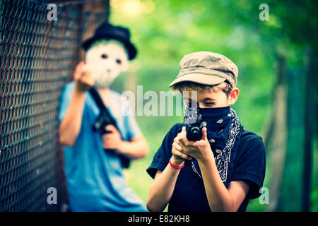 Ragazzo mascherato mirando con pistola giocattolo Foto Stock