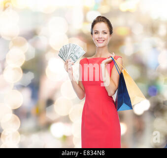 Donna sorridente in abito rosso con borse per lo shopping Foto Stock