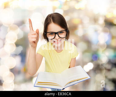 Sorridente bambina in occhiali con libro Foto Stock