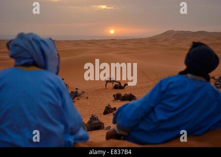 Berber uomini guardando sunrise, Erg Chebbi, il deserto del Sahara, Merzouga, Marocco Foto Stock