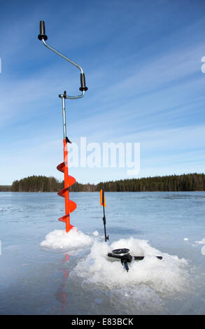 Coclea del ghiaccio a mano isolata e canna da pesca del ghiaccio a punta, Finlandia Foto Stock