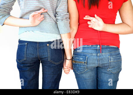 Due ragazze adolescenti in piedi tenendo le mani con le dita incrociate dietro le spalle; Regno Unito Foto Stock