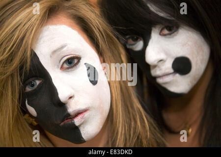 Caucasico due ragazze adolescenti l'età di 15 anni, avendo avuto le loro facce dipinte nel drammatico i colori nero e bianco, REGNO UNITO Foto Stock