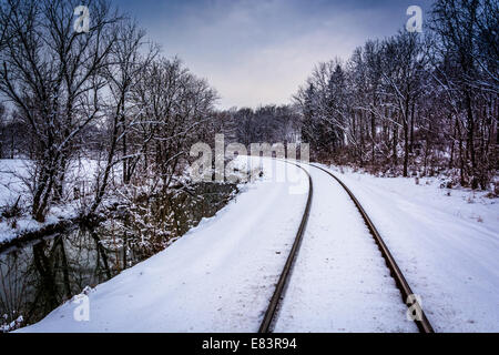 Coperta di neve i binari della ferrovia e creek nelle zone rurali Carroll County, Maryland. Foto Stock