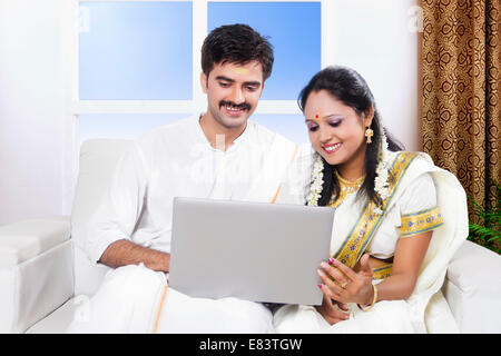 Sud indiane coppia sposata seduti a casa con il computer portatile Foto Stock