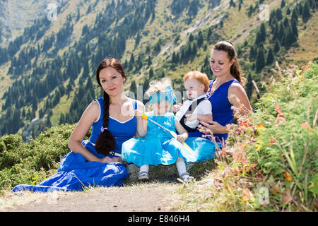 Due felici mamme e bambini ragazza e ragazzo costeggiata sulla natura del concetto di infanzia e famiglia. Foto Stock