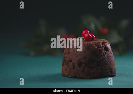 Pudding natalizio vestito con l'inverno bacche e foglie e spolverato con zucchero a velo Foto Stock