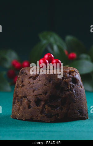 Pudding natalizio vestito con l'inverno bacche e foglie e spolverato con zucchero a velo Foto Stock