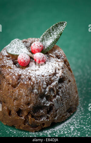 Pudding natalizio vestito con l'inverno bacche e foglie e spolverato con zucchero a velo Foto Stock