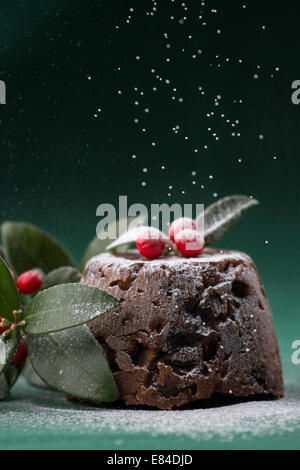 Pudding natalizio vestito con l'inverno bacche e foglie e spolverato con zucchero a velo Foto Stock