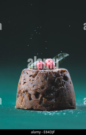 Pudding natalizio vestito con l'inverno bacche e foglie e spolverato con zucchero a velo Foto Stock