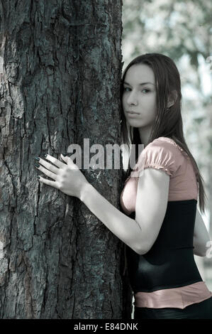 Una giovane donna che abbraccia un albero. Foto Stock