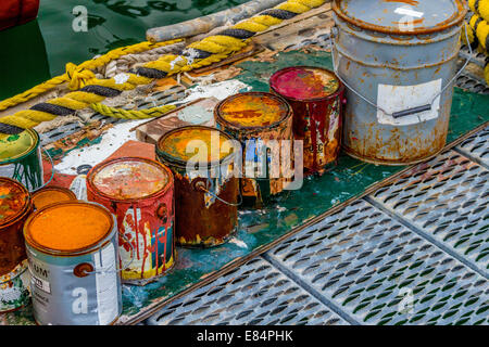 Colorato rusty barattoli di vernice sul dock. Foto Stock