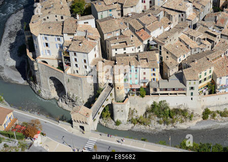 VISTA AEREA. Villaggio medievale ben protetto accessibile solo da un ponte sul fiume Var. Entrevaux, Alpi dell'alta Provenza, Francia. Foto Stock