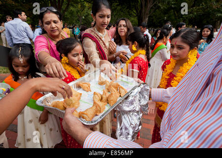 Folla di persone raccolte intorno ad una piastra di indiani Samosa Foto Stock