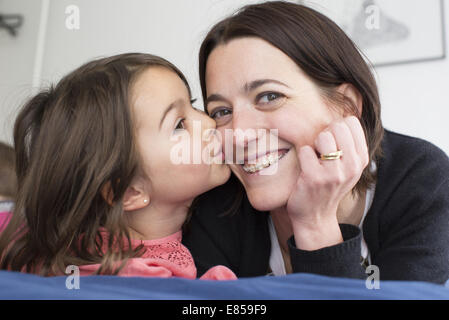 Piccola ragazza baciare la madre sua guancia Foto Stock