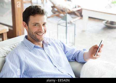 L'uomo utilizza lo smartphone, sorridente Foto Stock