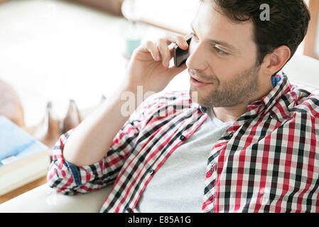 Uomo che parla su telefono cellulare a casa Foto Stock