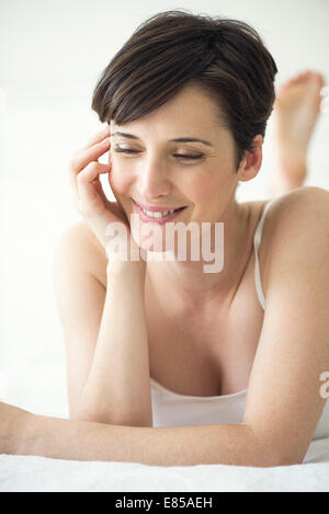 Donna sdraiata sul letto con aspetto di contentezza, ritratto Foto Stock