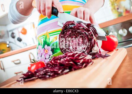 Donna con le mani in mano il taglio di cavolo rosso, dietro di verdure fresche. Foto Stock