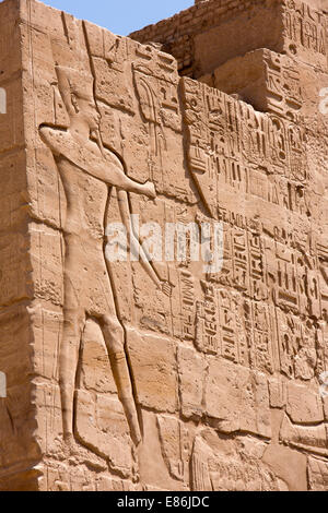 Egitto Luxor Tempio di Karnak, alto bassorilievo di uomo con la falce al fianco di geroglifici Foto Stock