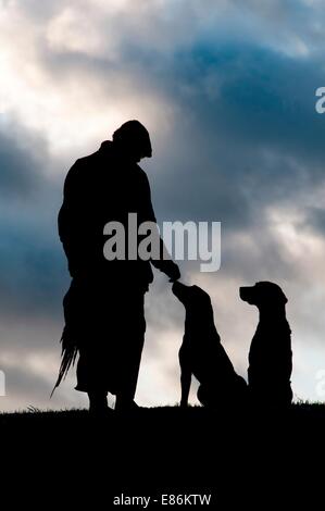 Un cacciatore e il suo cane stagliano contro il cielo Foto Stock