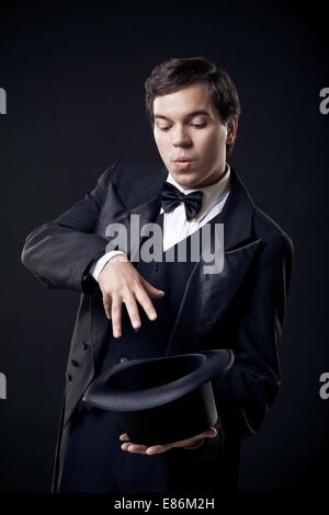 Il mago che mostra i trucchi con top hat isolato su sfondo scuro Foto Stock
