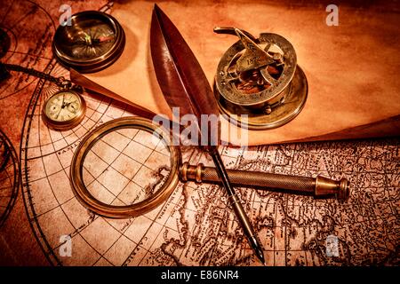 Vintage lente di ingrandimento, bussola, goose quill penna e un orologio da tasca giacente su una vecchia mappa. Foto Stock