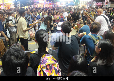 Hong Kong. 1 Ottobre, 2014. Hong Kong le proteste: musicisti -- incluso Hong Kong-base chitarrista americano A.B.A. Taft (L) -- Gioco di pro-democrazia manifestanti e per lo shopping nel distretto commerciale di Causeway Bay nei pressi del Sogo Department Store. Essi eseguono accanto a quello che probabilmente è il più trafficato attraversamento pedonale nel mondo. Credito: Robert Kemp SC/Alamy Live News Foto Stock