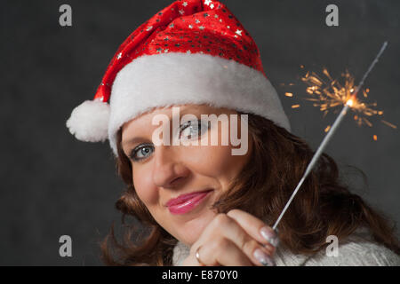 Closeup colpo di sorridere le donne in santa hat. Ragazza carina a Santa hat holding botti Foto Stock