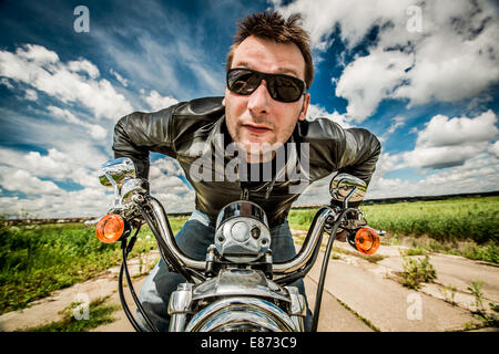 Biker in occhiali da sole e giacca di pelle racing su strada Foto Stock