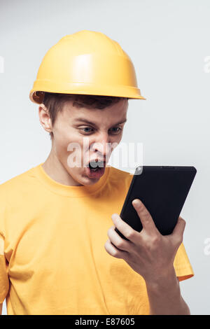 L'uomo lavoratore in un casco guarda tablet pc Foto Stock