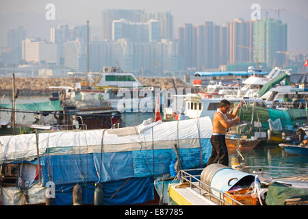 Uomo cinese su una barca in villaggio galleggiante. Il Causeway Bay Typhoon Shelter, Hong Kong. Foto Stock