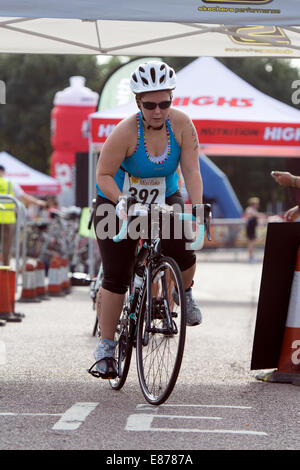 Concorrente femmina sulla bicicletta lasciando l'area di transizione al Warwickshire Triathlon, Stratford-upon-Avon, Regno Unito Foto Stock