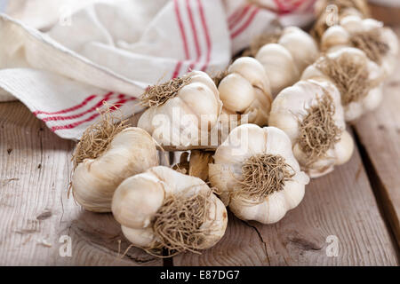 Treccia di bulbi di aglio sul vecchio tavolo in legno. Foto Stock