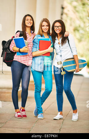 Azienda di felice teen ragazze guardando bianco della fotocamera in piedi vicino college Foto Stock