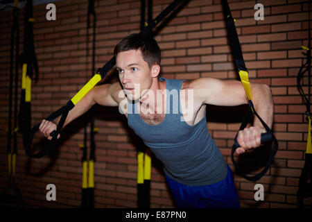 Giovane uomo facendo esercizi per i muscoli del braccio in palestra Foto Stock