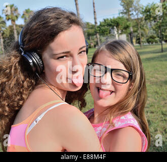 Due ragazza goofing intorno e leggere su un prato in posizione di parcheggio Foto Stock