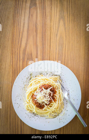 Piatto di spaghetti con la carne di suolo il ragù alla bolognese e parmigiano grattugiato su tavola in legno rustico. Foto Stock