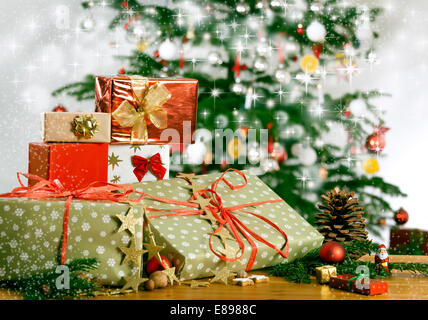 Molti doni su una tabella e un albero di Natale con sfondo scintillante Foto Stock