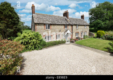 Una bella e tradizionale inglese costruito in pietra cottage impostato nella campagna di Wiltshire sotto un sole cielo estivo Foto Stock
