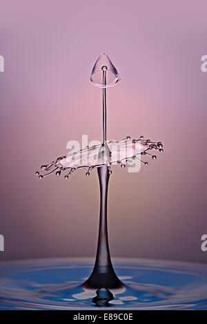 Un alto acqua goccia rimbalza da una piscina di acqua di collidere con altre gocce formando una scultura d'acqua. Foto Stock