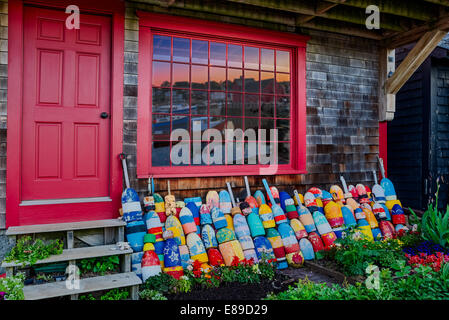 Righe di boe colorate allineate in una vetrina con motivo Numero Uno riflessa nella finestra riquadri. Bradley Wharf a Rockport, Massachusetts. Foto Stock