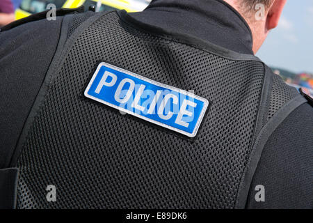 Un caucasico maschio britannico poliziotto che indossa la polizia moderna uniforme con la polizia di parola cucita sul retro del suo gilet tattico Foto Stock